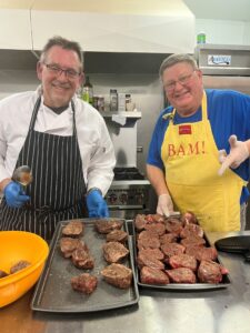 Lions Paul Hopfaulf and Craig Anderson prepare a gourmet meal for the banquet.